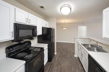an empty kitchen with white cabinets and black appliances